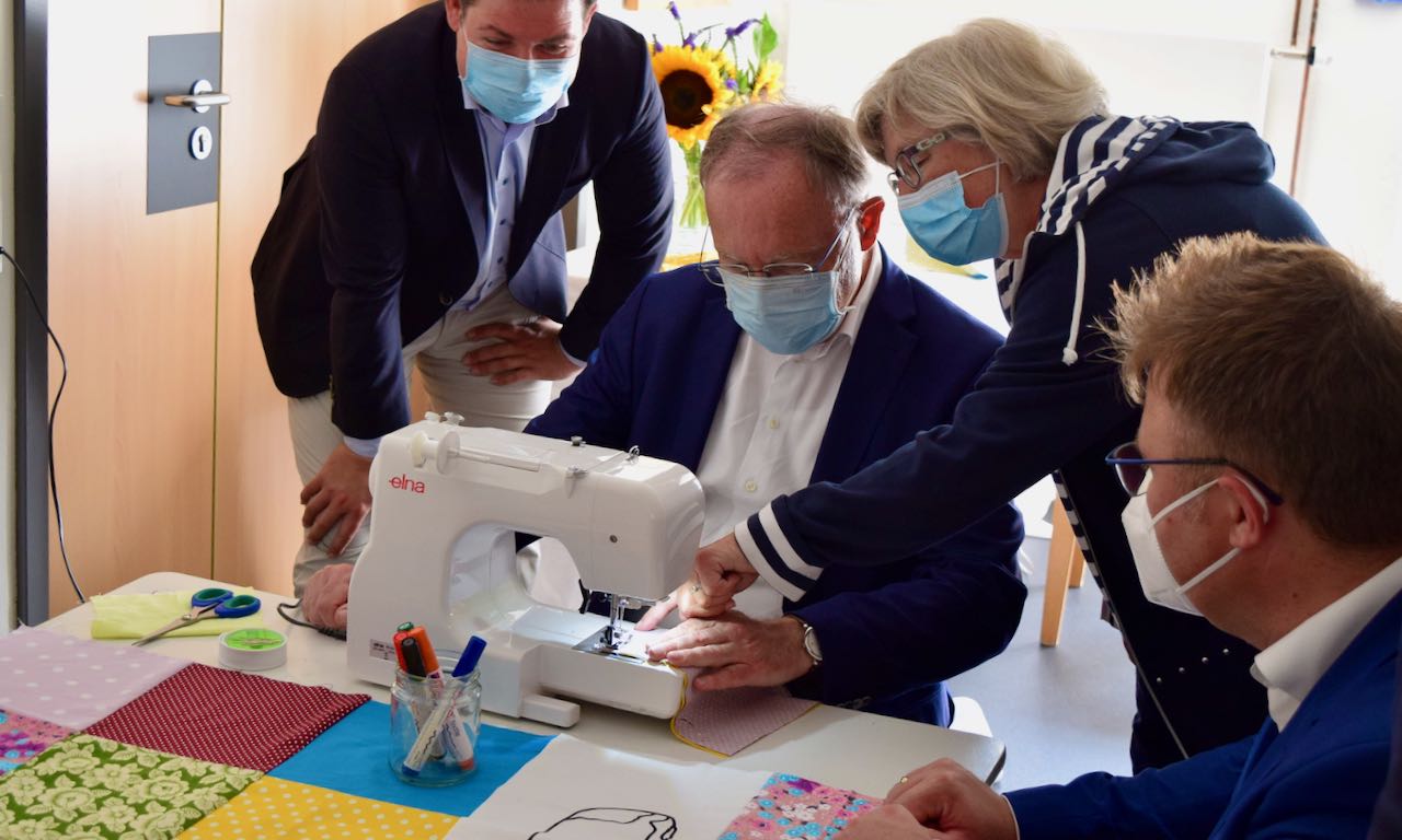 Stephan Weil näht unter Anleitung von Bärbel Schneegans.