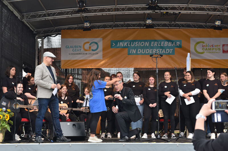 Die Viertklässlerin, die im Video als Aribo die Weihe vollzog, bat Bischof Heiner Wilmer auf die Bühne, um ihm als „Bischöfin Adeleida“ zu demonstrieren, wie die Weihe damals durch Handauflegen erfolgte. | Foto: Iris Blank